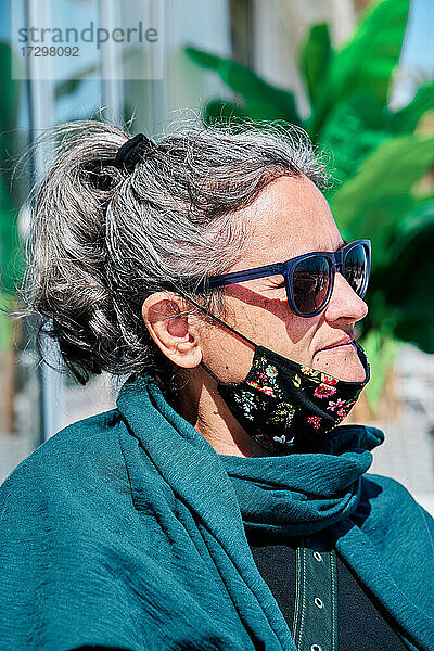 Porträt einer Frau mittleren Alters mit weißem Haar  Sonnenbrille und einer Maske unter dem Mund