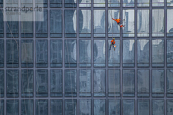 Fensterputzer bei der Arbeit an der Fassade eines Hochhauses in Bangkok