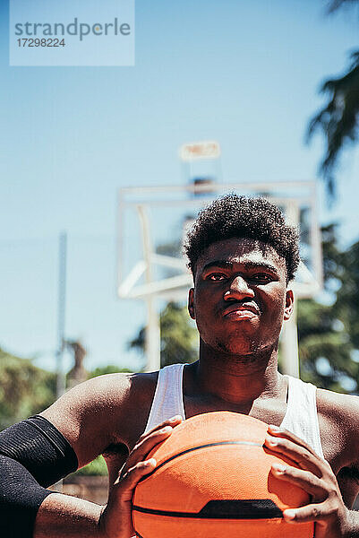 Porträt eines wütenden schwarzen Afro-Jungen mit trotzigem Blick  der den Basketball mit seinen Händen zusammendrückt. Bereit  ein Spiel zu spielen.