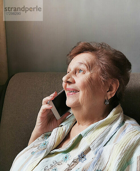 Ältere Frau spricht am Handy und lächelt fröhlich
