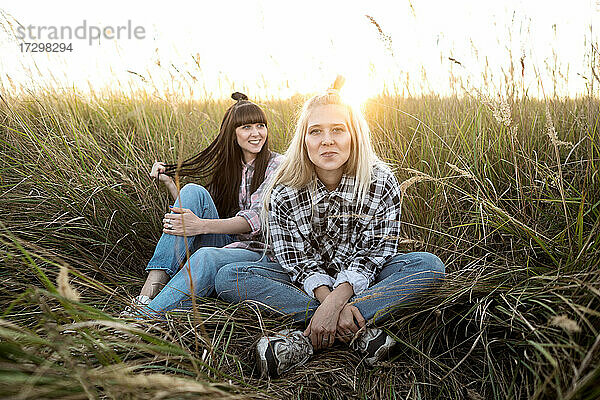 zwei schöne Zwillingsmädchen machen Stil im Feld bei Sonnenuntergang