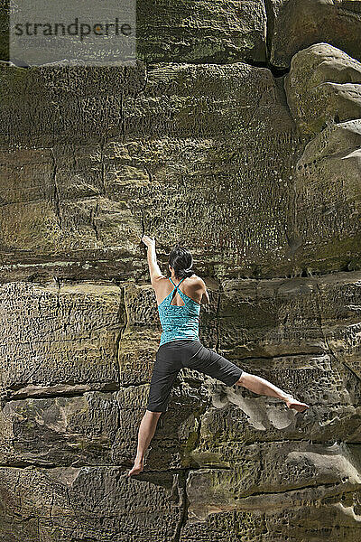 Frau beim Bouldern an den Sandsteinfelsen von Harrison's Rock in England