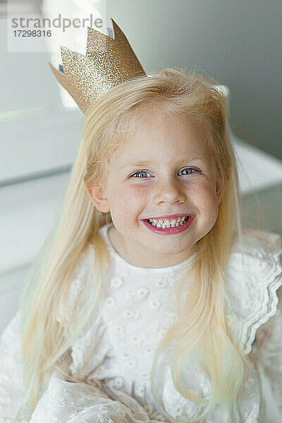 Glückliches blondes Mädchen lächelnd mit goldener Krone.