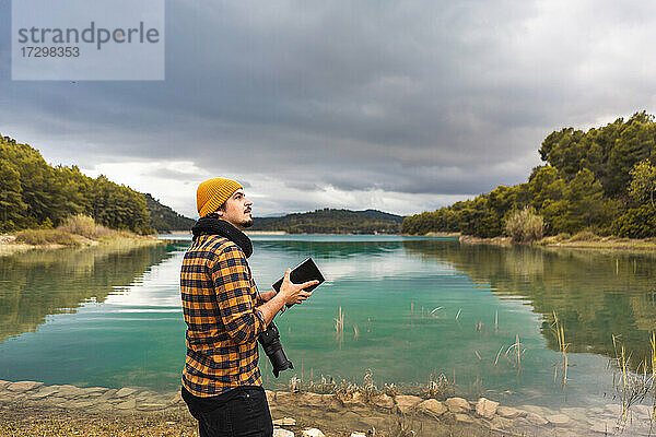Fremdenführer mit Hut und Kamera im See  der ein Reiseführerbuch liest