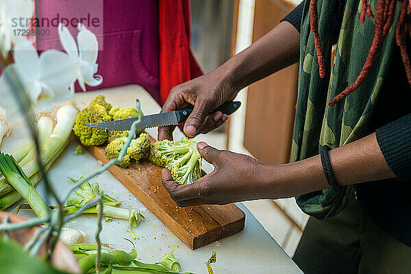 Schwarze Frau schneidet Brokkoli  in der Küche