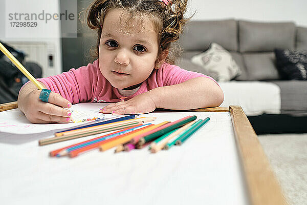 Das Mädchen sitzt an ihrem Schreibtisch und zeichnet mit ihren Bleistiften.