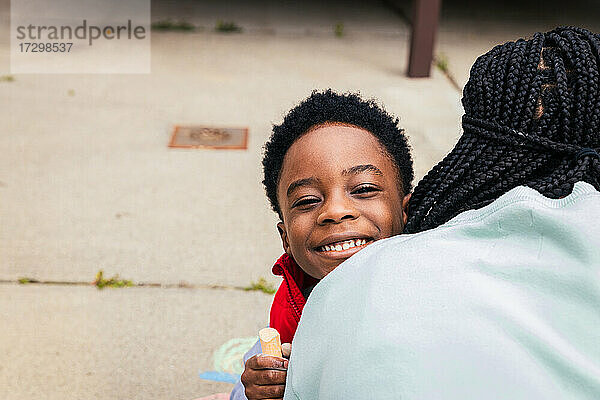 Lächelnder Sohn umarmt Mutter im Hinterhof