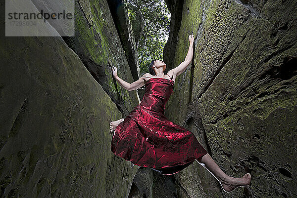 Frau in rotem Kleid beim Bouldern an den Sandsteinfelsen