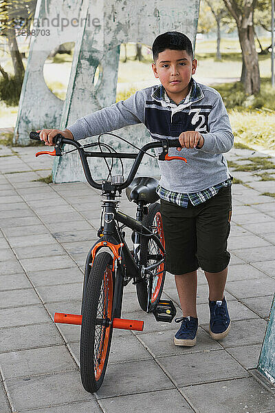 Ein Junge geht mit seinem Fahrrad spazieren.