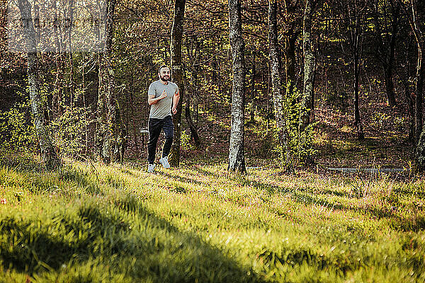 Mann mit Mütze und dunklem Trainingsanzug läuft durch den Wald