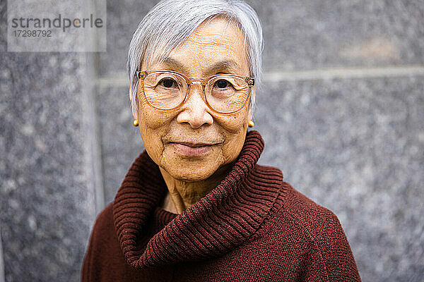 Porträt einer lässigen älteren Frau mit Blick in die Kamera in städtischer Umgebung