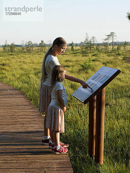 Kinder stehen im Naturschutzgebiet und betrachten die Informationstafel