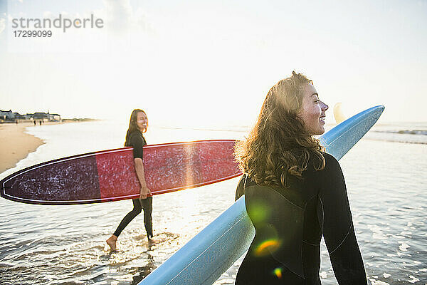 Zwei Freundinnen gehen zum Sonnenaufgang zum Surfen
