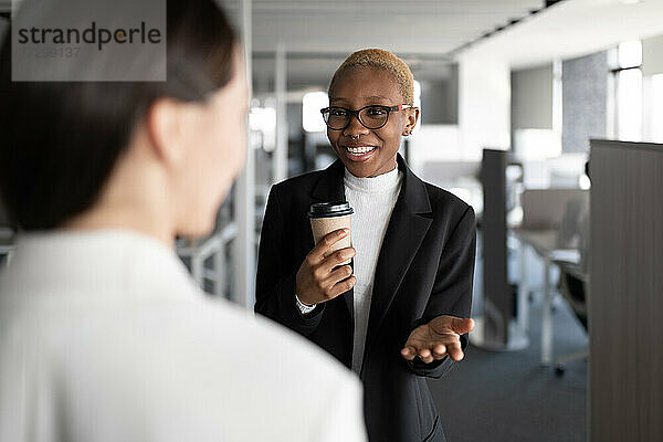 Fröhliche schwarze Geschäftsfrau im Gespräch mit einem Kollegen