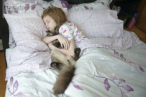 Krankes kleines Mädchen schläft im Bett mit Katze