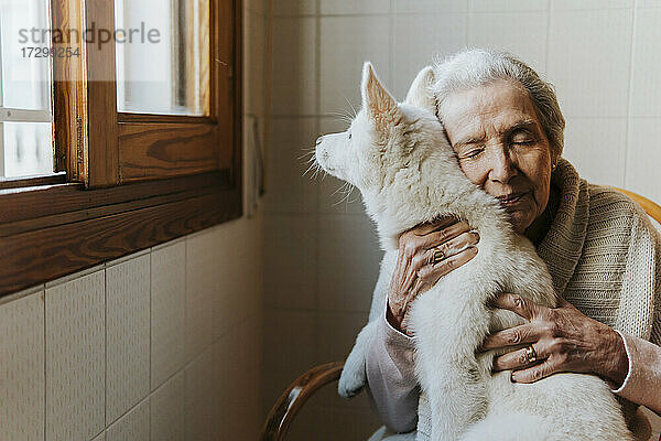 Ältere Frau umarmt zärtlich ihren weißen Siberian Husky Welpenhund