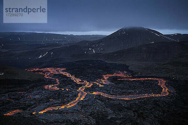 Heiße Lava strömt an einem rauen Vulkanhang im nächtlichen Hochland