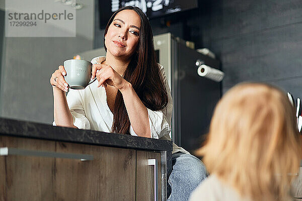 schöne Frau beim Kaffeetrinken in der Küche