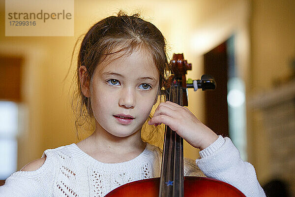 Nahaufnahme eines süßen Mädchens  das zu Hause Cello übt