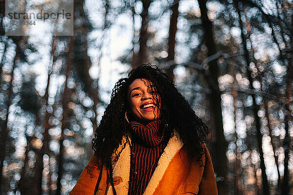 Porträt einer glücklichen jungen Frau  die im Winter im Wald steht