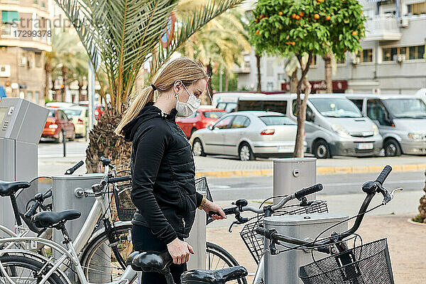 Eine junge Frau benutzt ein gemietetes Fahrrad  bevor sie Sport treibt