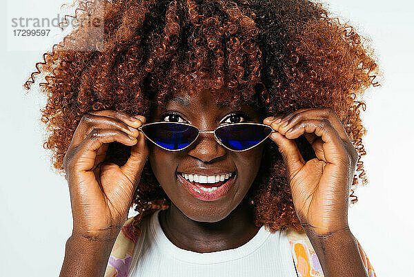 Schwarze junge Frau mit Sonnenbrille schaut in die Kamera