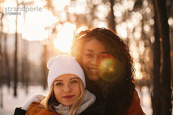 Porträt von glücklichen Freundinnen  die sich im Winter im Park umarmen
