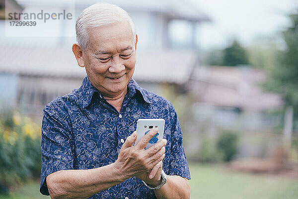 Glücklicher asiatischer älterer Mann mit Smartphone.
