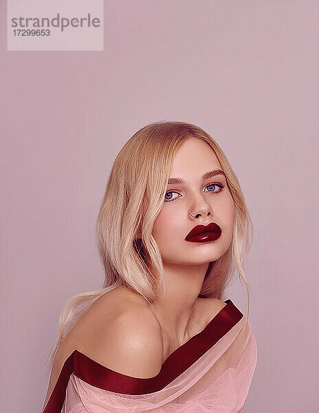 Schönheit Mode Modell Porträt mit glänzenden blonden Frisur mit roten Lippen auf rosa Hintergrund