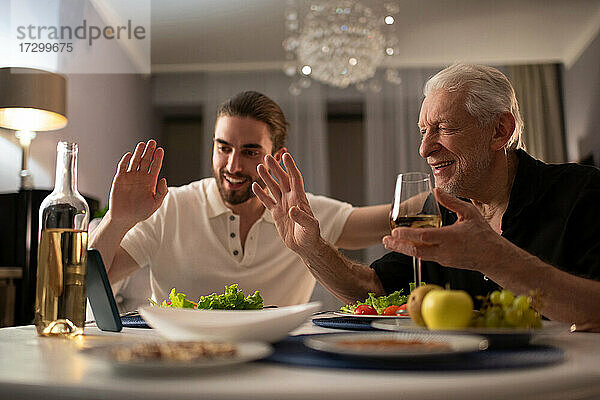 Großvater und Enkel grüßen online Verwandte beim Abendessen