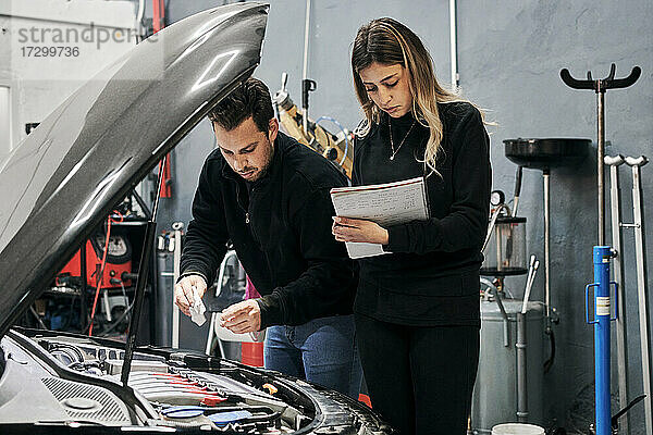 Zwei Mechaniker helfen sich gegenseitig bei der Arbeit in einer Werkstatt
