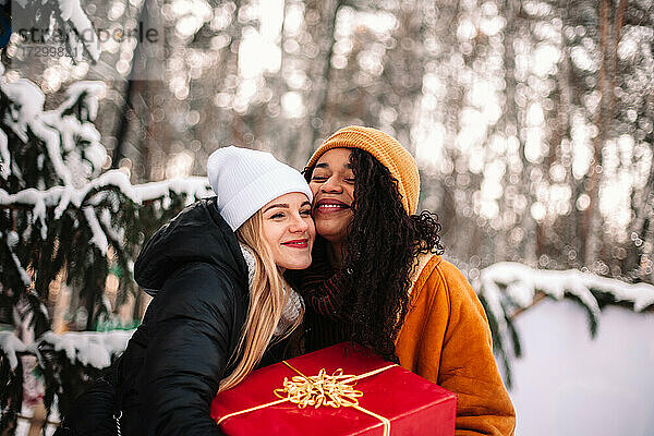 Glückliche Freundinnen mit Weihnachtsgeschenken unter dem Weihnachtsbaum