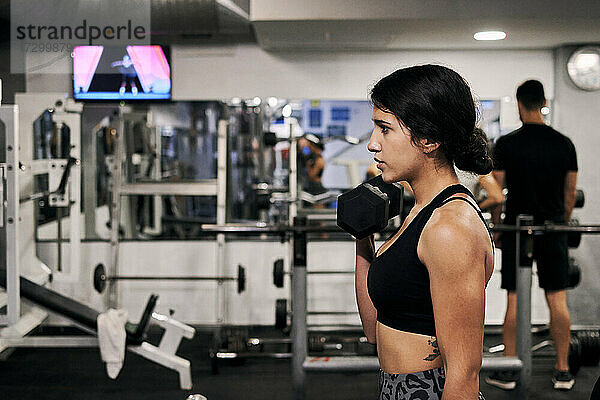 Junge Frau hebt Gewichte in einem Fitnessstudio