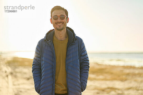 glücklicher junger Mann mit Sonnenbrille am Strand
