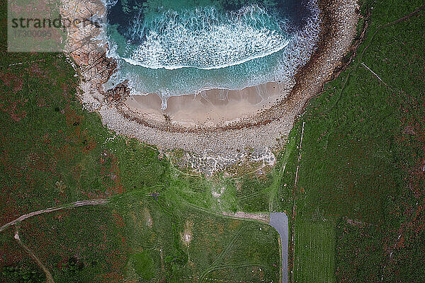 Draufsicht einer Drohne auf einen wilden Strand mit grüner Landschaft in Galicien  Spanien