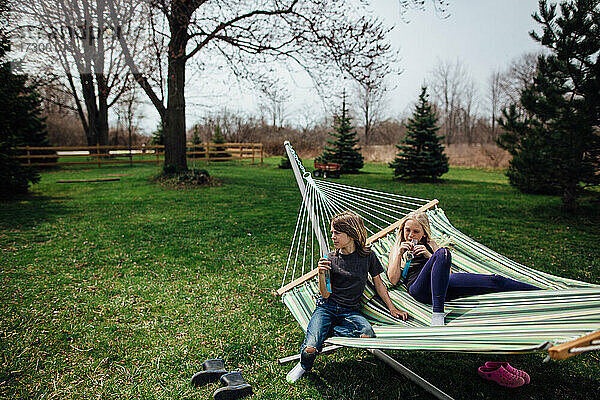 Junge und Mädchen entspannen sich auf einer Hängematte im Hinterhof im Frühling