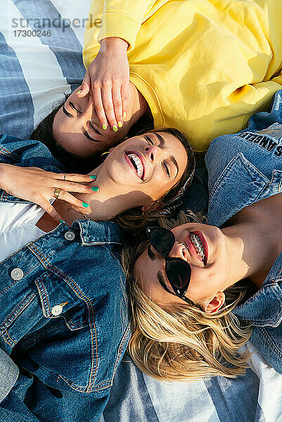 Overhead-Porträt von lächelnden Freunden  die am Strand liegen und Spaß haben
