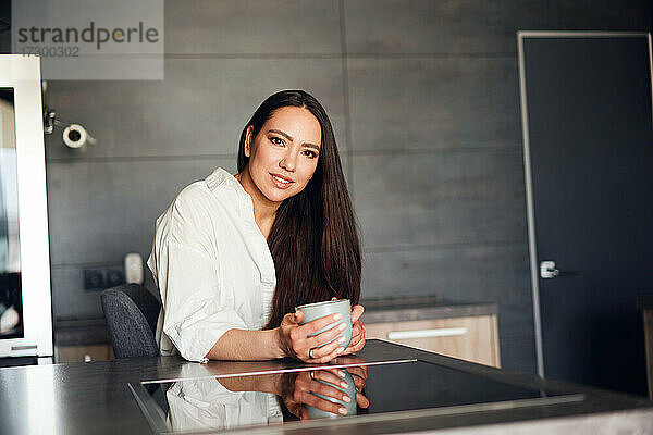 schöne Frau beim Kaffeetrinken in der Küche