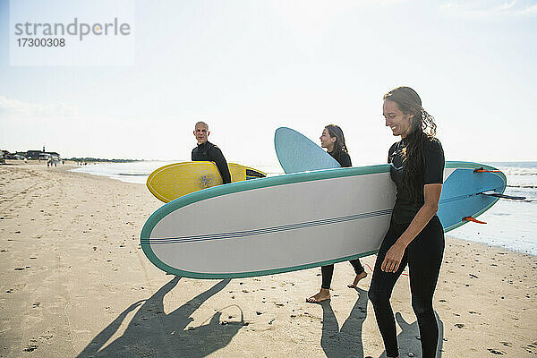 Gruppe von Surferfreunden beim Surfen im Sommer bei Sonnenaufgang