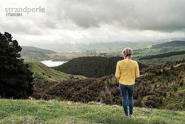 Tween Mädchen in gelben Pullover Blick auf See von Hügeln in Neuseeland