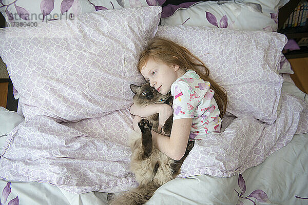 Krankes kleines Mädchen kuschelt mit Katze im Bett