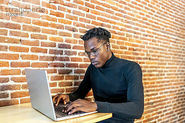 junger afrikanischer Mann  der an seinem Laptop arbeitet