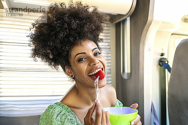 Hübsche afrikanische Frau isst eine gesunde Erdbeere