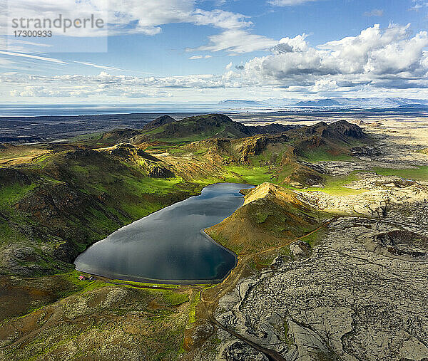 Drohnenansicht eines ruhigen Sees in bergigem Gelände an einem bewölkten Tag in Island