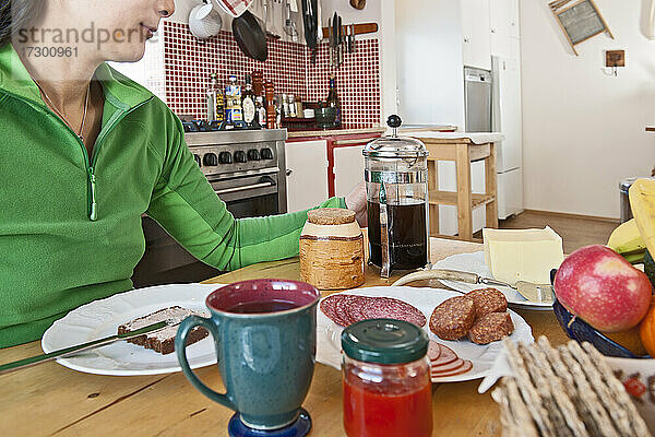 Frau beim Frühstück am Küchentisch in Island