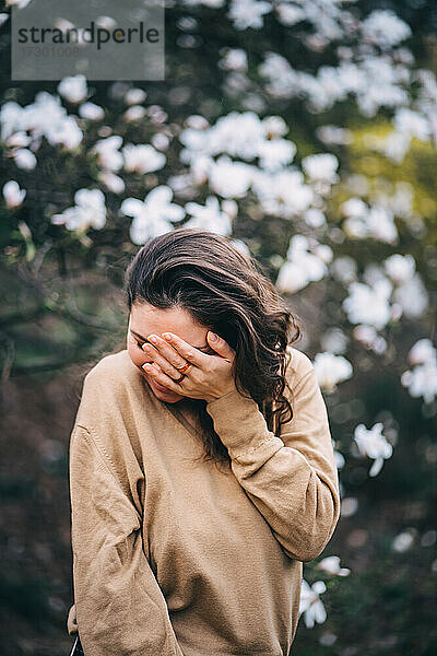 schönes Mädchen lacht im Park mit Magnolien