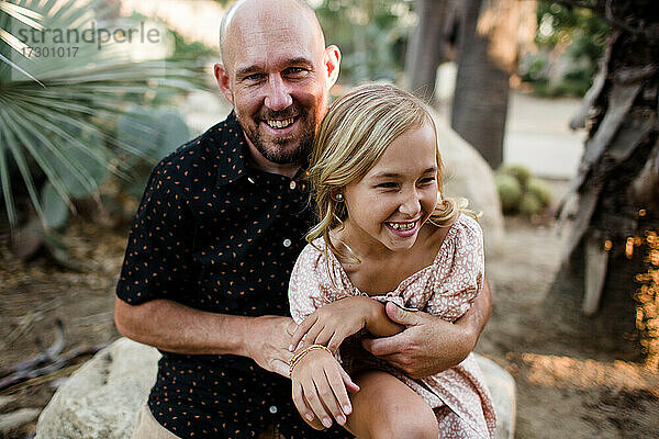 Vater kitzelt Tochter im Garten in San Diego
