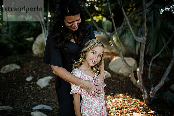 Mutter umarmt junge Tochter im Garten in San Diego