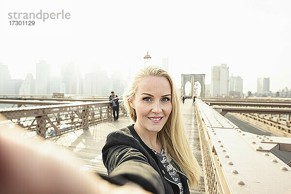 Lächelnde Frau nimmt Selfie auf städtischen Stadt Brücke