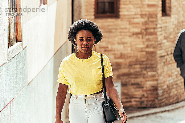 Porträt eines schwarzen afro-amerikanischen Mädchens  das eine Straße in der Altstadt entlanggeht.